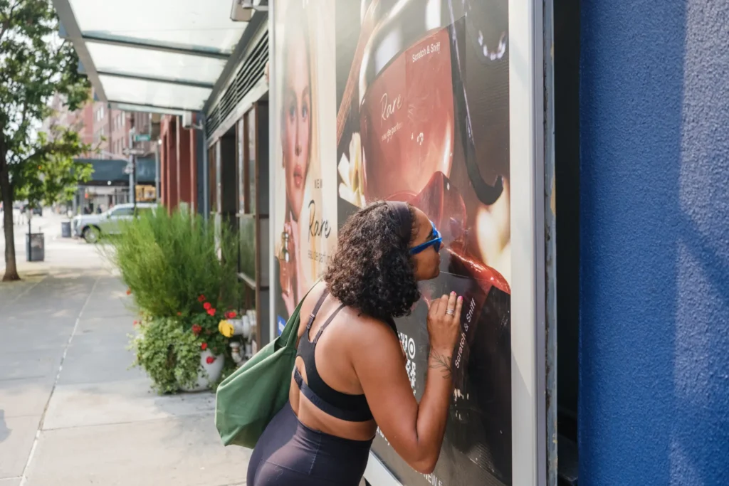 Rare Beauty’nin “scratch-and-sniff” billboardunu kazıyarak vanilya kokusunu alan Melanie Peralta, deneyimini gerçekleştiriyor.