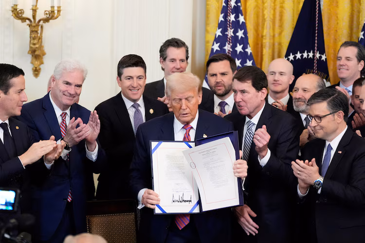 Donald Trump, 18 Temmuz 2025'te Washington'daki Beyaz Saray'ın Doğu Odası'nda, bir kripto para türü olan stablecoin'leri düzenleyen bir yasa tasarısı olan GENIUS Yasası'nı imzaladıktan sonra imzalı belgeyi gösteriyor.